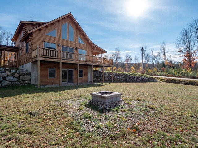 back of house with a fire pit, log exterior, a deck, and a yard