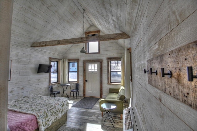 living area featuring wooden walls, lofted ceiling with beams, and wood finished floors