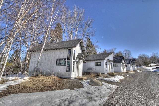 view of snow covered exterior featuring roof with shingles