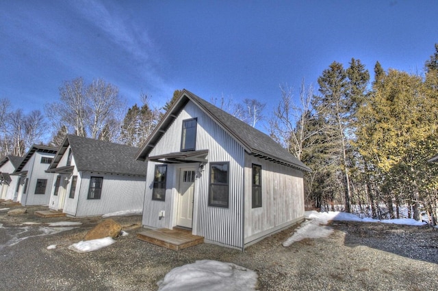 view of front of house with a shingled roof and an outdoor structure