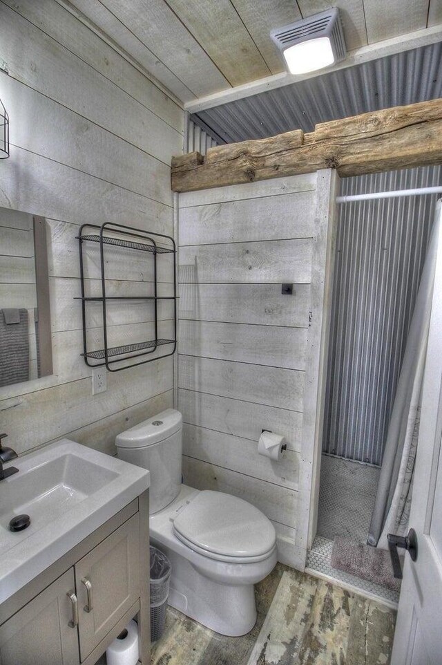 bathroom with visible vents, toilet, wood walls, vanity, and wood finished floors