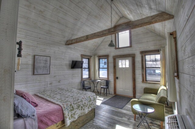 bedroom with vaulted ceiling with beams, wood walls, and wood finished floors