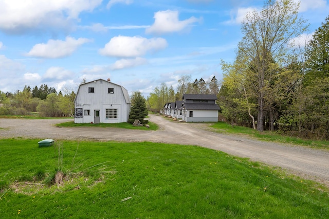 2342 Main St, Rangeley, ME 04970 - view of front of home featuring a gambrel roof, driveway, a front lawn, an outdoor structure, and a barn