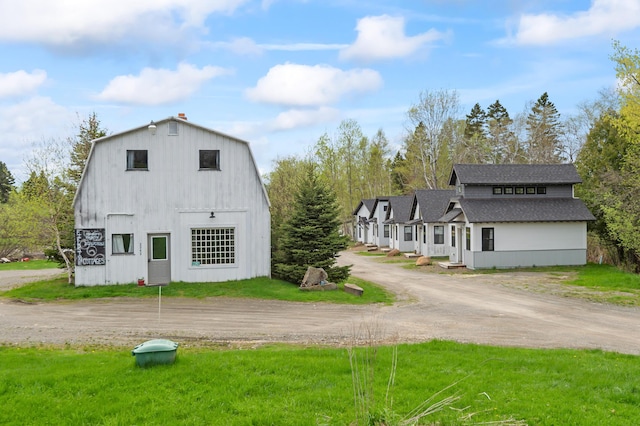 2342 Main St, Rangeley, ME 04970 - view of property exterior featuring driveway, roof with shingles, a lawn, and a gambrel roof
