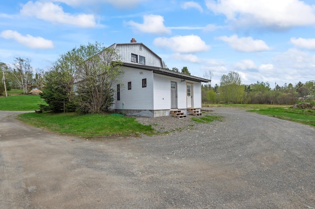 2342 Main St, Rangeley, ME 04970 - view of side of home featuring entry steps, driveway, a chimney, and a yard