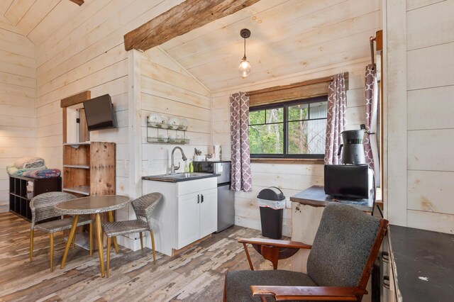 2342 Main St, Rangeley, ME 04970 - kitchen featuring a sink, wood finished floors, dark countertops, wood walls, and white cabinets