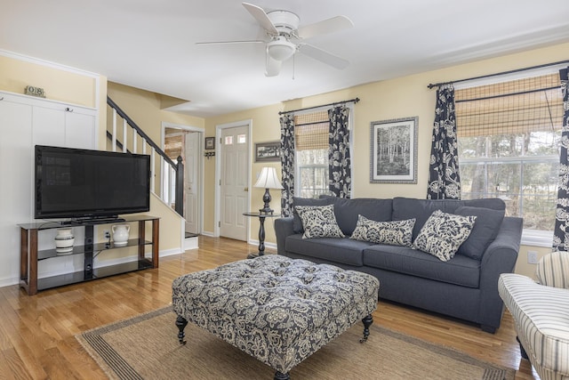 living area with stairway, baseboards, ceiling fan, and wood finished floors