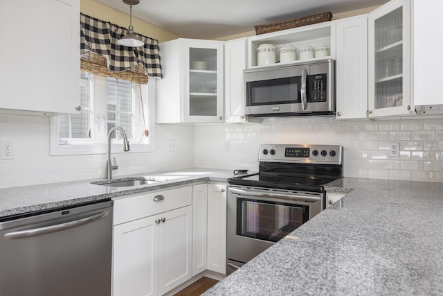 kitchen with a sink, white cabinets, light stone countertops, and stainless steel appliances