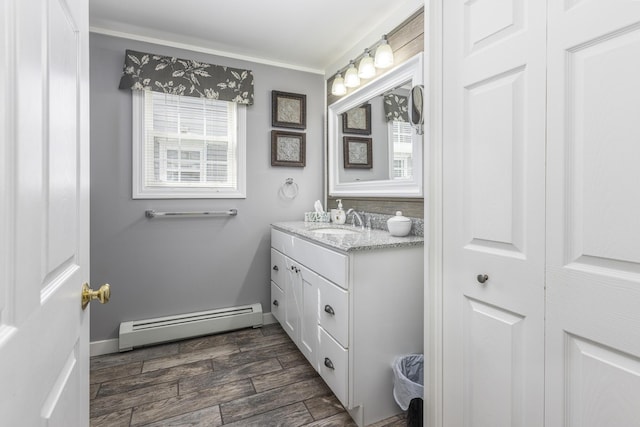 bathroom featuring a healthy amount of sunlight, vanity, a baseboard heating unit, and wood finish floors