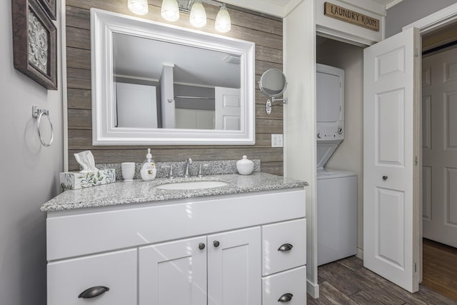 bathroom featuring vanity, wood finished floors, and stacked washer and clothes dryer