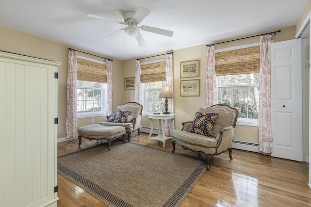 living area featuring a baseboard radiator, light wood-style floors, and a ceiling fan