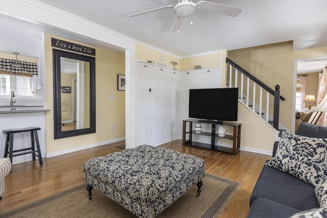 living area featuring ceiling fan, stairway, baseboards, and wood finished floors