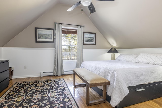 bedroom featuring vaulted ceiling, a baseboard heating unit, ceiling fan, and wood finished floors