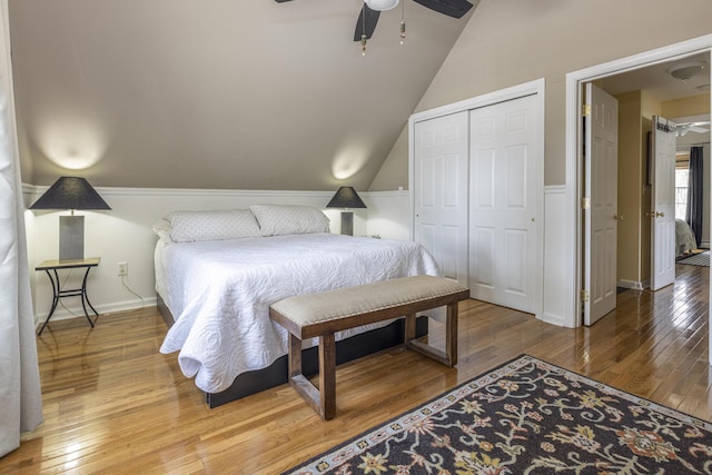 bedroom featuring ceiling fan, baseboards, lofted ceiling, hardwood / wood-style flooring, and a closet