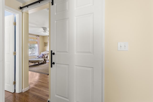 hall with a barn door and dark wood finished floors