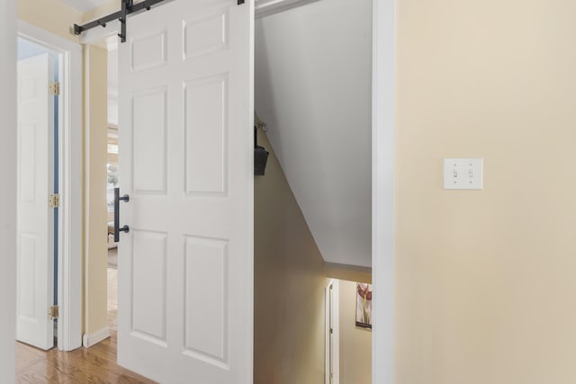 hallway featuring a barn door and wood finished floors