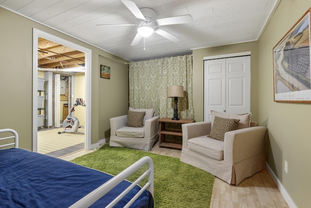 bedroom with a closet, baseboards, wood finished floors, and a ceiling fan