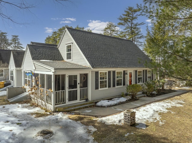 rear view of house featuring a sunroom and a shingled roof