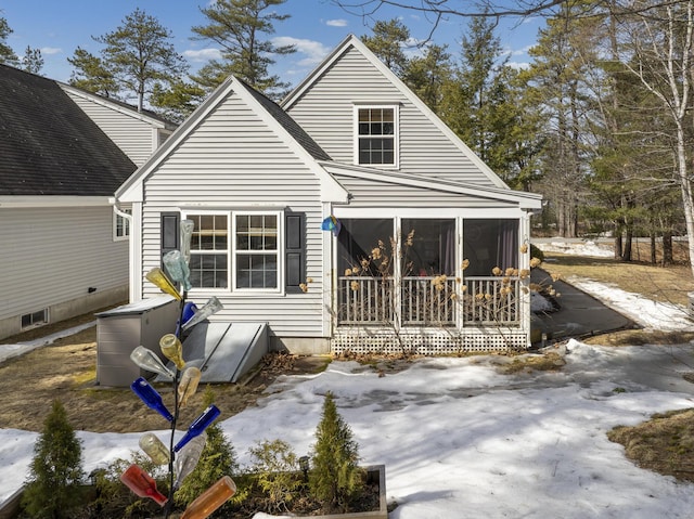 snow covered house featuring a sunroom