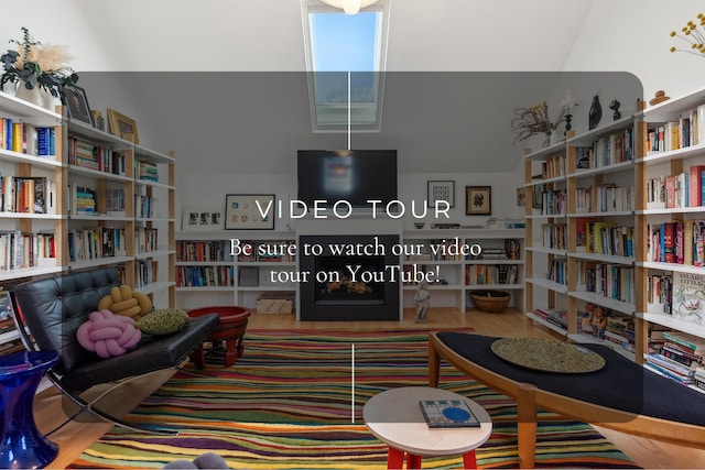 living area with wood finished floors, a fireplace, and bookshelves