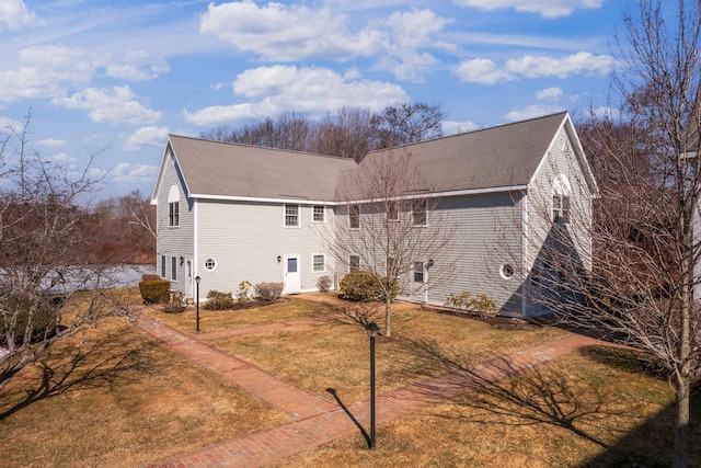 view of home's exterior with a yard and a shingled roof