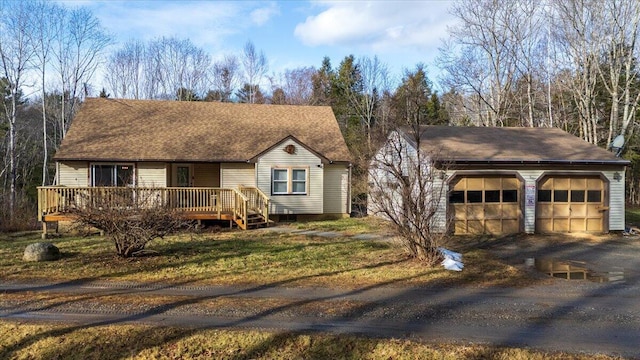 view of front of house with a wooden deck, an outbuilding, and roof with shingles