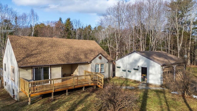 back of house featuring an outbuilding, a wooden deck, and a shingled roof