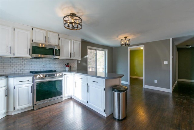 kitchen featuring appliances with stainless steel finishes, a peninsula, white cabinets, and an inviting chandelier