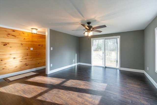 spare room featuring dark wood finished floors, a ceiling fan, and baseboards