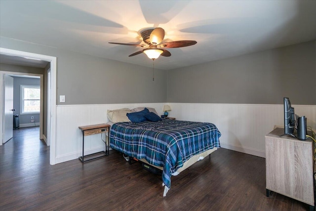 bedroom featuring wood finished floors, a wainscoted wall, and ceiling fan