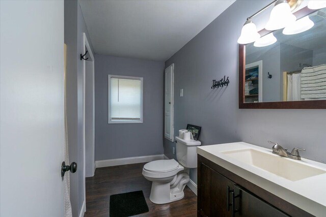 full bathroom with toilet, curtained shower, wood finished floors, baseboards, and vanity