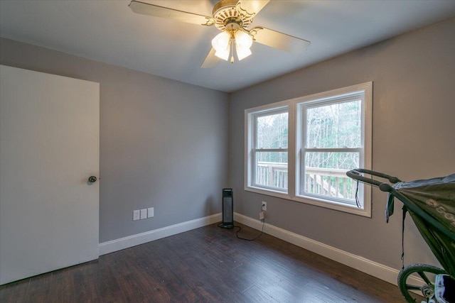 spare room with ceiling fan, baseboards, and dark wood-style flooring