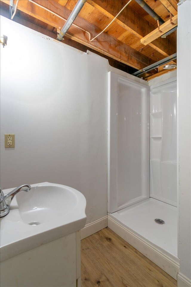 full bathroom featuring baseboards, wood finished floors, a stall shower, and vanity