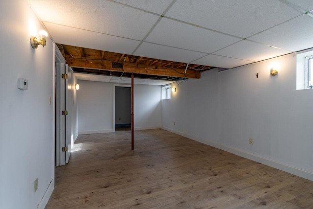 below grade area featuring wood finished floors, baseboards, and a drop ceiling