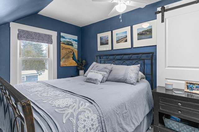 bedroom with ceiling fan, a barn door, and vaulted ceiling