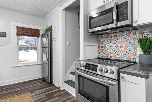 kitchen featuring an ornate ceiling, stainless steel appliances, dark wood-type flooring, white cabinets, and dark countertops