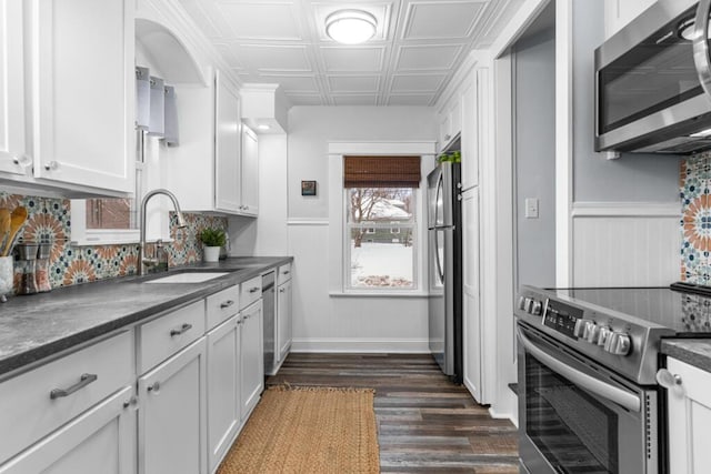 kitchen featuring dark countertops, an ornate ceiling, stainless steel appliances, and a sink