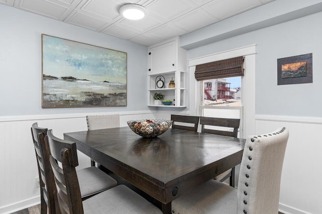 dining room featuring a wainscoted wall, an ornate ceiling, and baseboards