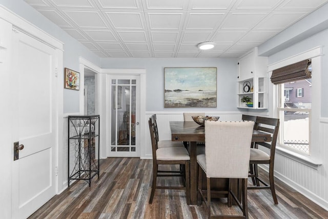 dining space featuring wainscoting, an ornate ceiling, and dark wood-type flooring