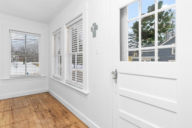 doorway to outside featuring baseboards and wood finished floors