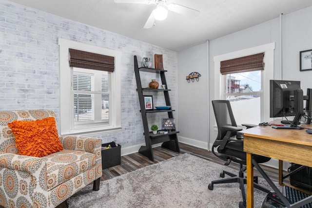 office space with a ceiling fan, wood finished floors, baseboards, and brick wall