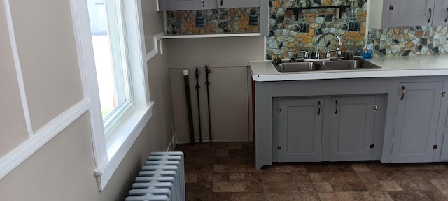 interior space with a sink, stone finish flooring, radiator heating unit, and light countertops