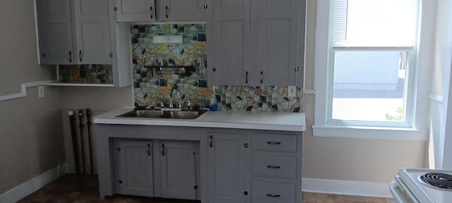 kitchen featuring a sink, tasteful backsplash, white electric stove, light countertops, and baseboards