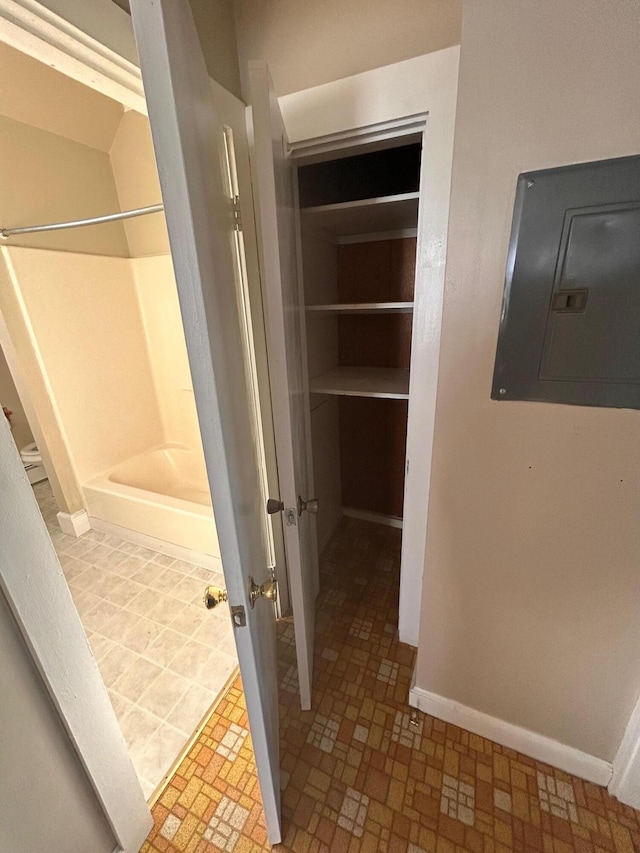 interior space with electric panel, a shower, and baseboards