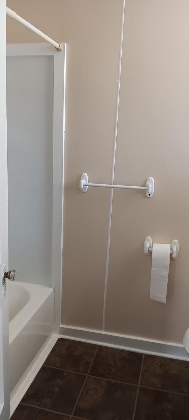 bathroom with tile patterned floors, a bathtub, and baseboards