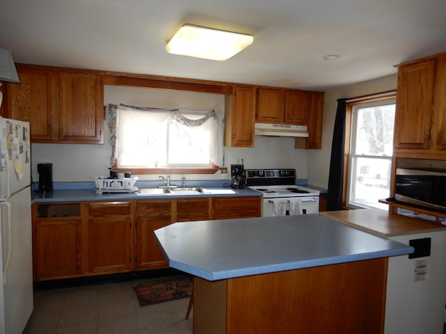 kitchen featuring under cabinet range hood, white appliances, brown cabinetry, and a sink