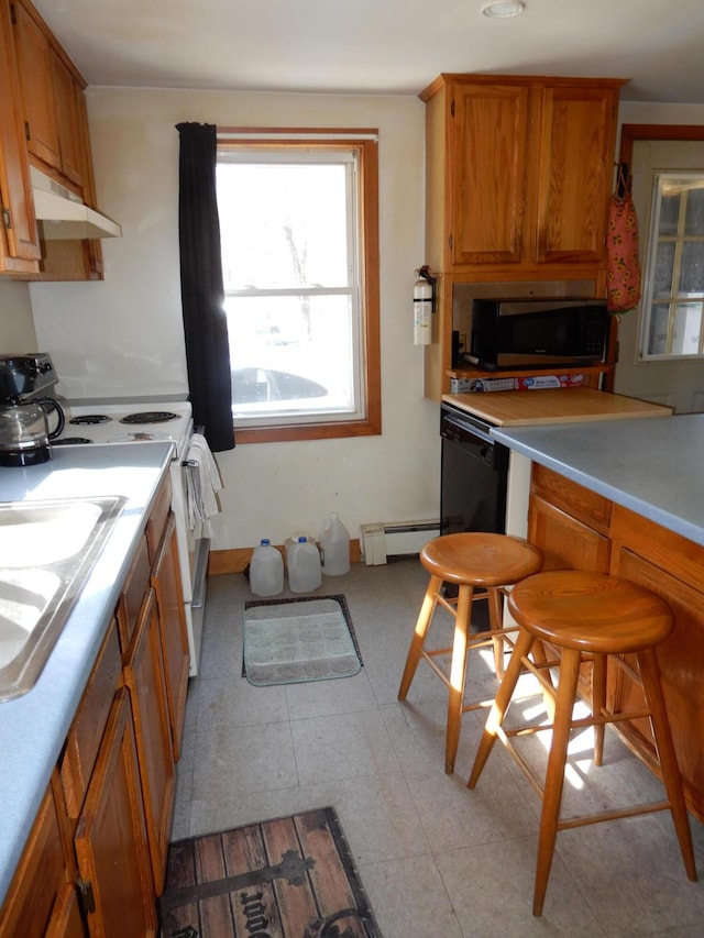 kitchen with stainless steel microwave, a baseboard heating unit, light countertops, brown cabinetry, and electric range