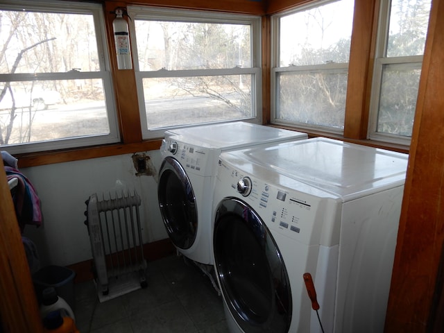 laundry room featuring washer and dryer, laundry area, radiator heating unit, and a healthy amount of sunlight