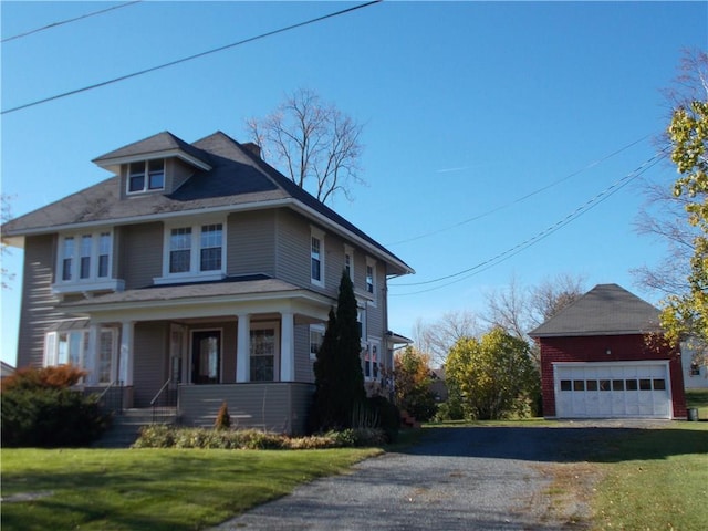 american foursquare style home with a porch, a front yard, and an outdoor structure