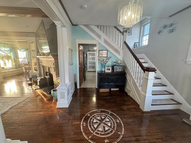 staircase with plenty of natural light, wood finished floors, and decorative columns